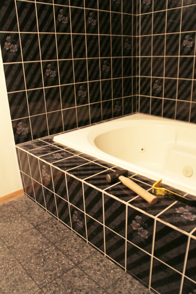 En suite bathroom with jetted tub and black tile surround