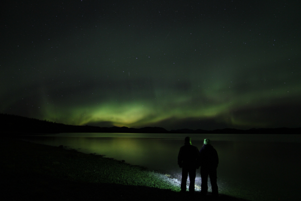 A couple under the Northern lights at Lake Laberge, Yukon