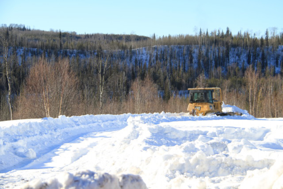 Bulldozer making trails through deep snow for bison
