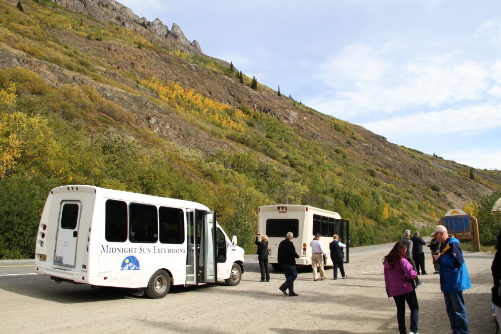 Tour buses at the Welcome to the Yukon sign