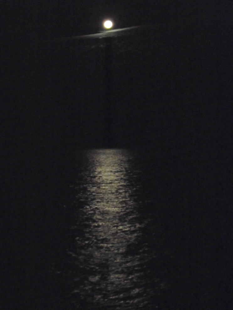 A nearly-full moon glistening on the ocean