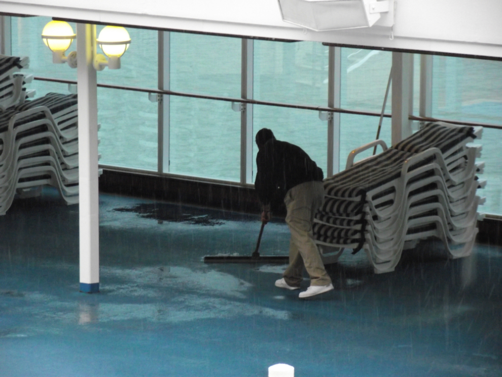 Pushing water off the deck of the rain-soaked Coral Princess