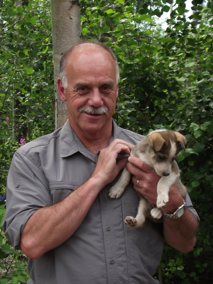 Tour guide Murray Lundberg with a husky puppy at the Iditarod headquarters