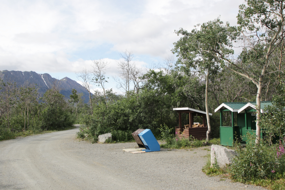 Outhouses, wood box and garbage cans at Conrad Campground, Yukon.