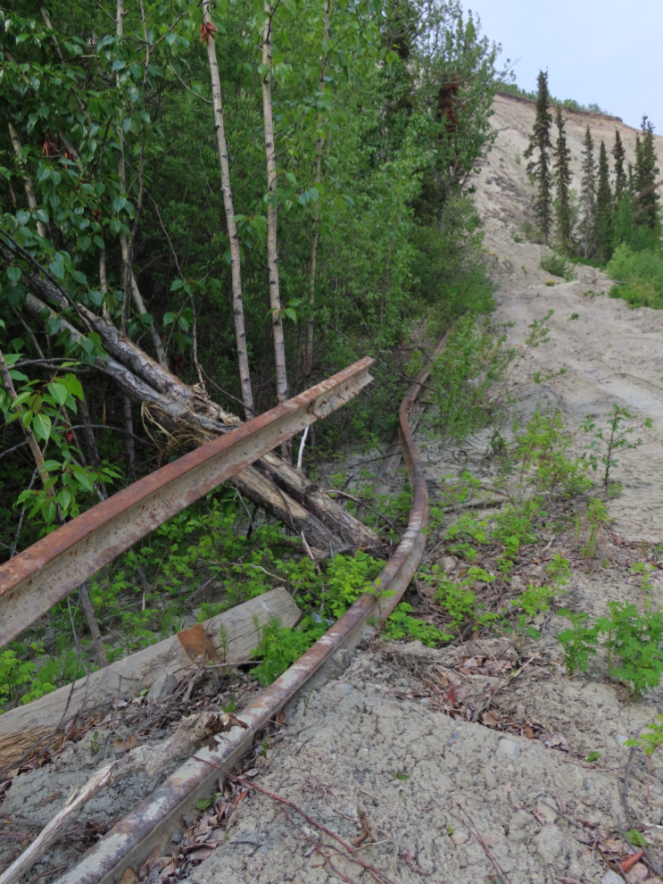 Twisted rails from the historic White Pass & Yukon Route rail line that was torn up to install a metal sheet piling wall along Robert Service Way in 2022 as a slide barrier.