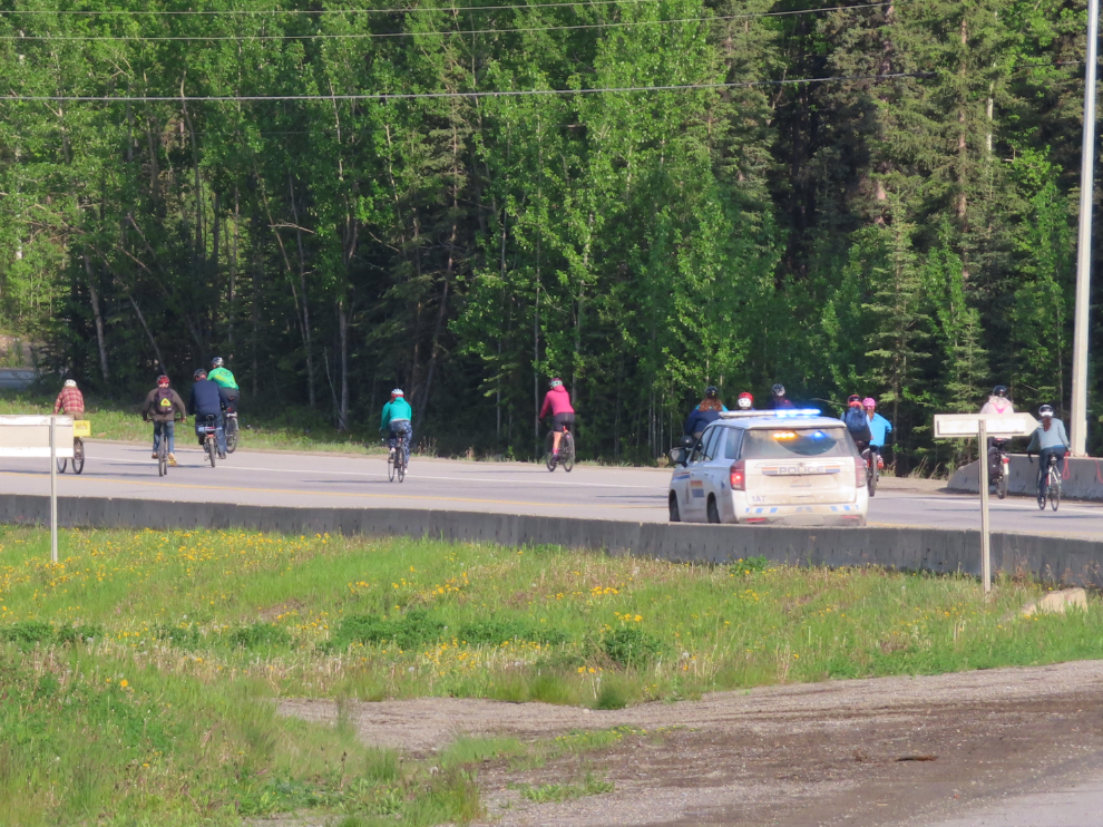 An RCMP cruiser on an emergency call goes by the Joe Morrison memorial bike ride in Whitehorse, Yukon.