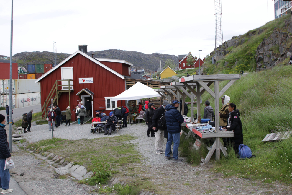 A multi-artist sale table set up by the dock at Qaqortoq, Greenland.