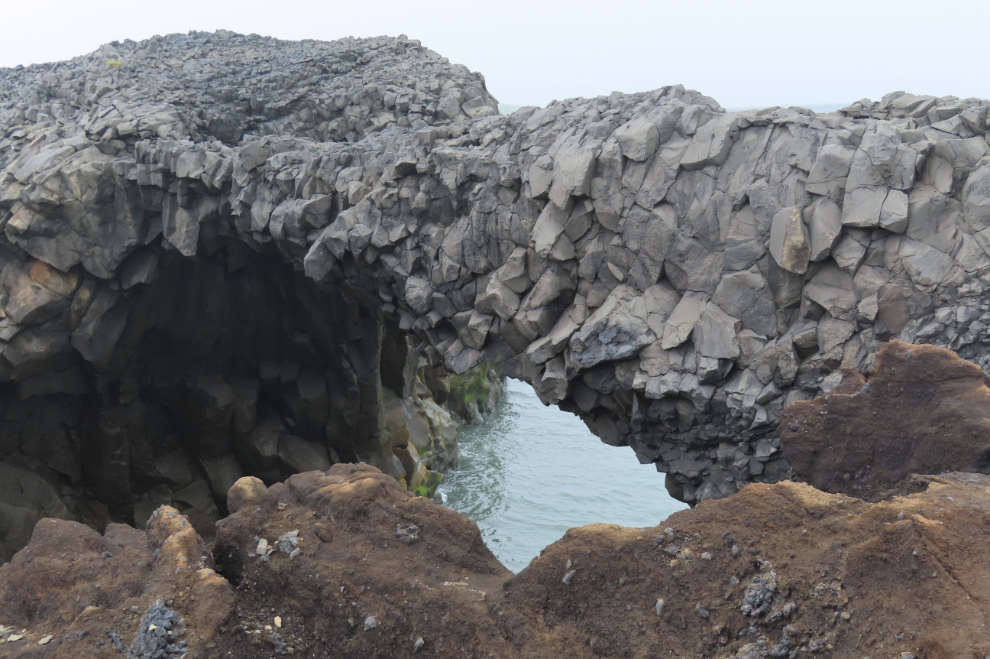 A basalt arch at Dyrholaey on Iceland's South Coast, in heavy fog and volcanic smoke. 