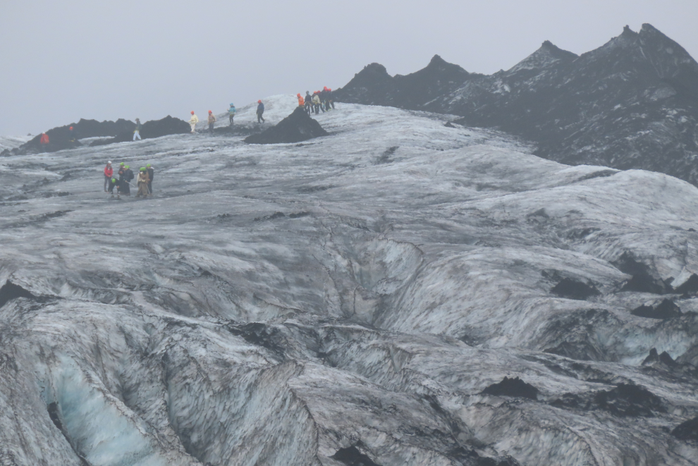 People walking on the glacier Solheimajokull on Iceland's South Coast, in heavy fog and volcanic smoke. 