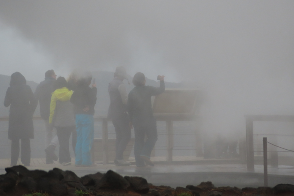 Gunnuhver Hot Springs, Iceland, with people almost hidden by steam and heavy volcanic smoke.