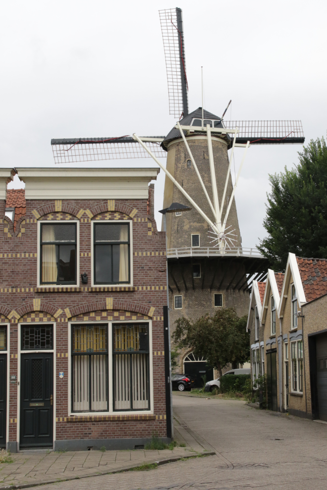 A streetscape that includes a windmill at at Gouda, South Holland, the Netherlands.