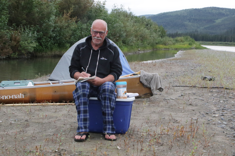 Murray Lundberg writing at camp while canoeing the Yukon River.