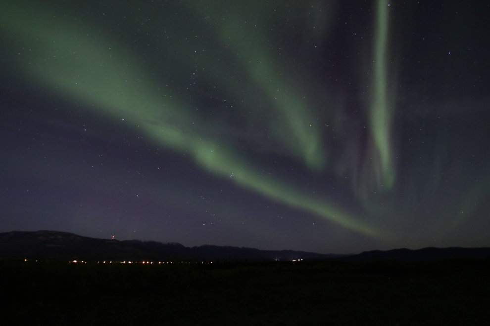 The Northern Lights at Whitehorse, Yukon, with the lights of the Alaska Highway below..