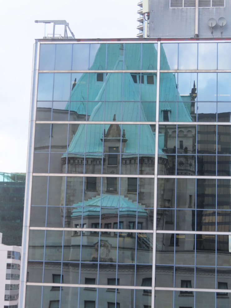 The Hotel Vancouver reflected in te windows of an office tower.