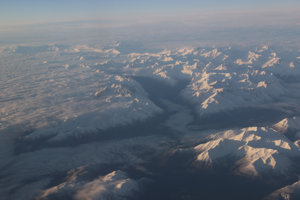 Snowy mountains above a layer of low cloud and valley fog, between Whitehorse and Vancouver.
